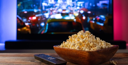 Home theater setup easy to use A popcorn bowl in fron of a home cinema screen with a remote control
